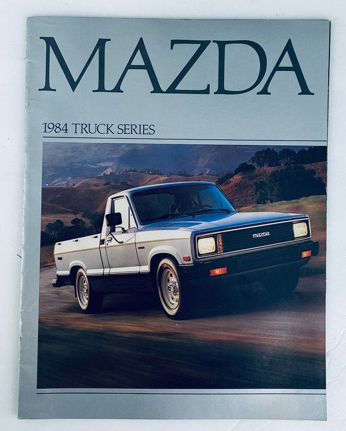1984 Mazda Truck Series Dealer Showroom Sales Brochure Guide Catalog featuring a front view of a silver Mazda truck against a scenic backdrop.