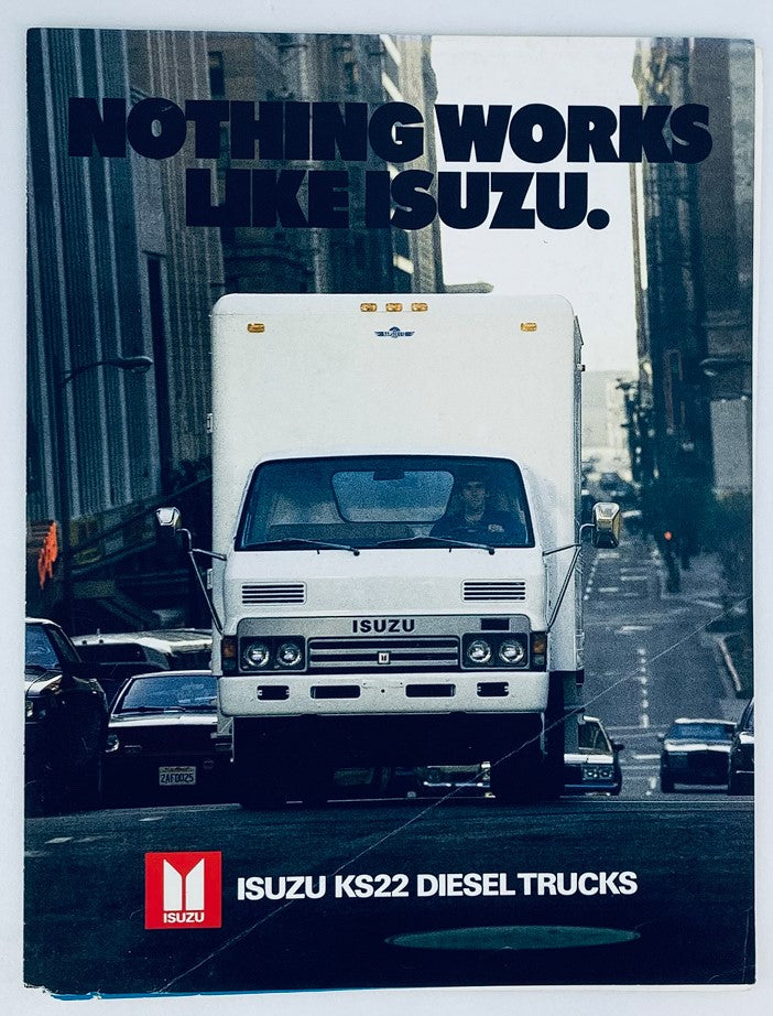 Cover of the 1984 Isuzu K22 Diesel Trucks Dealer Showroom Sales Brochure Guide Catalog featuring a prominent ISUZU truck on a city street with the slogan 'Nothing Works Like Isuzu.'