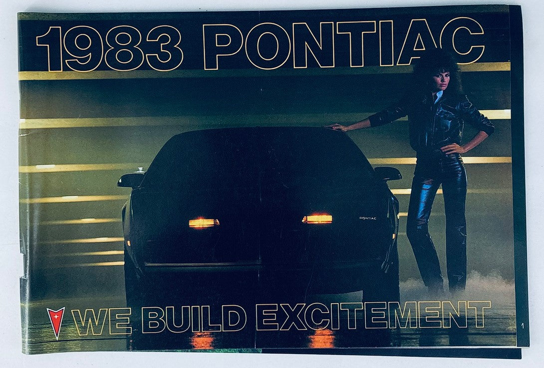 1983 Pontiac Lineup Dealer Showroom Sales Brochure Guide Catalog featuring a striking image of a Pontiac car with a model, embodying the theme 'We Build Excitement.'