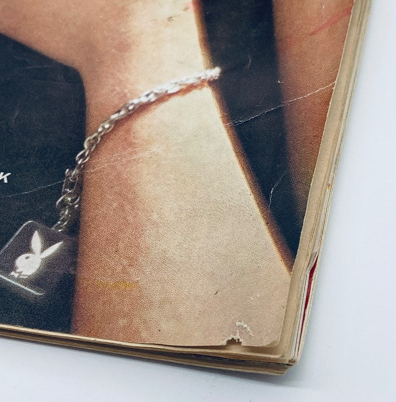 Detail shot of a vintage Playboy Magazine May 1960, featuring a close-up of a wrist adorned with a Playboy bunny logo bracelet.