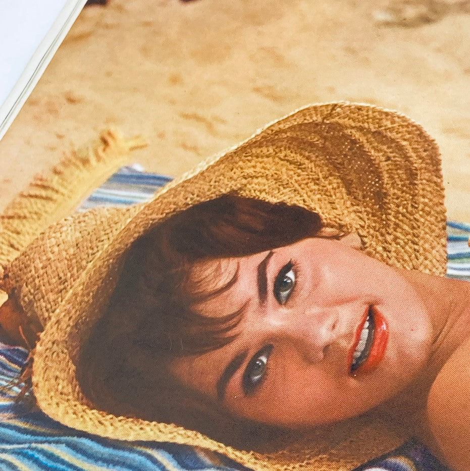 Close-up of Delores Wells, the featured Playmate in the June 1960 Playboy Magazine, showcasing her beauty with a straw hat and colorful beach attire.