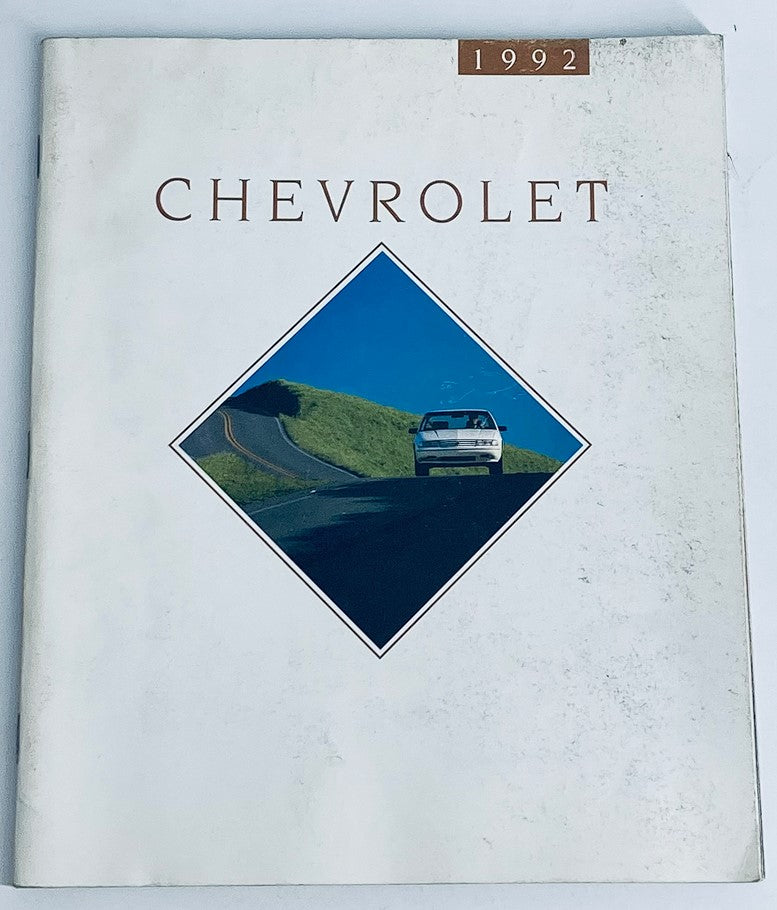 Cover of the 1992 Chevrolet Full Lineup Dealer Showroom Sales Brochure Guide Catalog featuring a car driving on a scenic road with a green landscape.