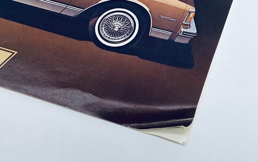 Close-up view of the corner of the 1982 Chevrolet Caprice Classic & Impala Dealer Showroom Sales Brochure Catalog, showcasing a vintage design with a detailed illustration of the Caprice Classic. Visible damage includes creases and a fold at the bottom edge, indicative of its age.