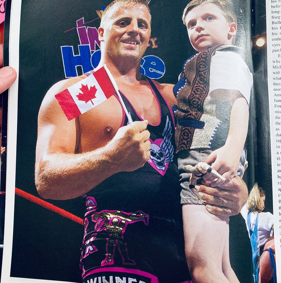 WWF World Wrestling Federation Magazine Owen Hart Tribute 1965-1999 - A memorable photo of Owen Hart holding a Canadian flag with a child, showcasing his connection with fans.