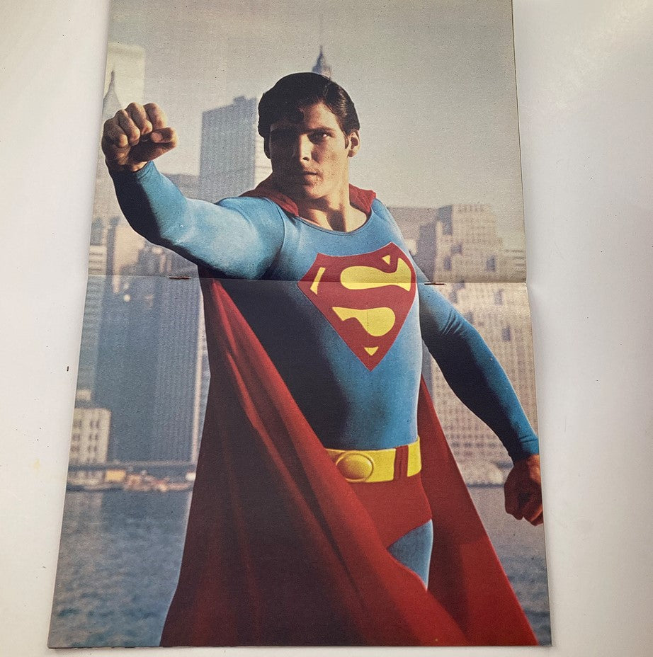 Superman The Movie Comic Books (1978 Merit Publications) featuring Superman in a striking pose with a city skyline in the background. This image showcases the iconic character, emphasizing his heroic stance and vibrant costume.