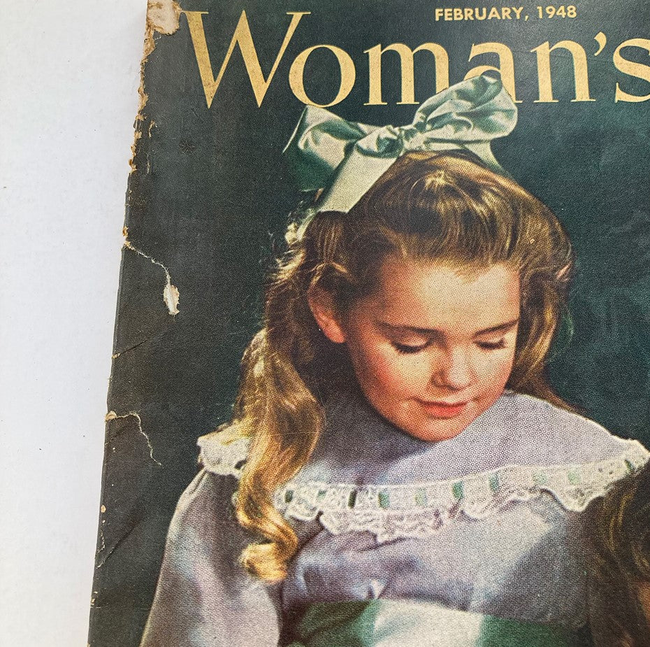 Close-up of the cover of VTG Woman's Day Magazine February 1948, showcasing a young girl with a bow in her hair, emphasizing the vintage style and charm.