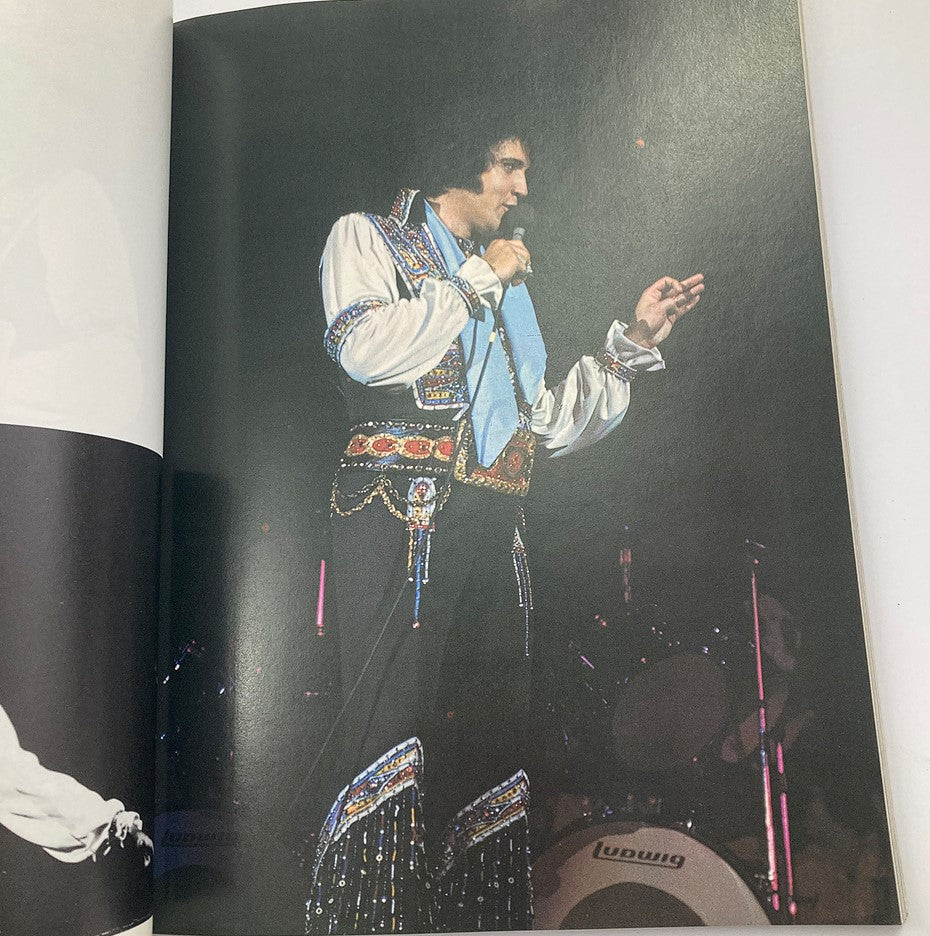 Vintage 1979 Elvis in Concert by John Reggero A Delta Special showing Elvis Presley singing into a microphone while wearing an elaborate stage costume, surrounded by bright concert lights.