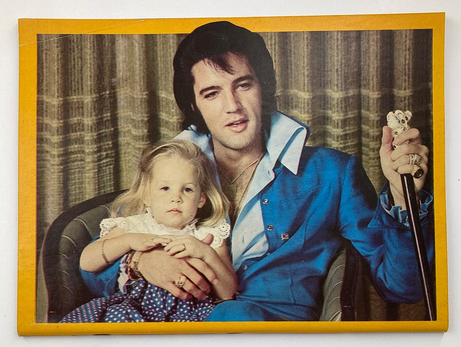 Elvis Presley holding a young girl in VTG Platinum Magazine 1979 The Elvis Presley Diary Journal with Poster, showcasing a tender moment captured in vintage photography.