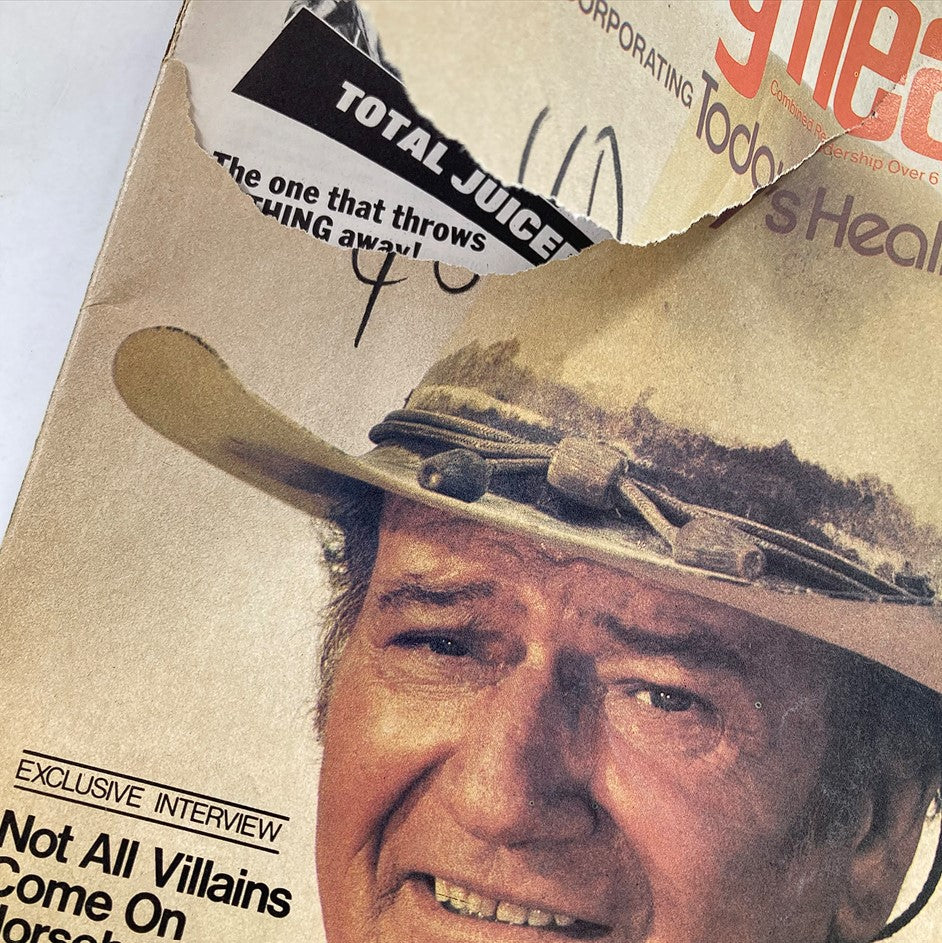 Detail of the damaged cover of VTG Family Health Magazine September 1976, displaying a portion of John Wayne's face, the title 'How John Wayne Conquered Cancer', and tears on the magazine cover.