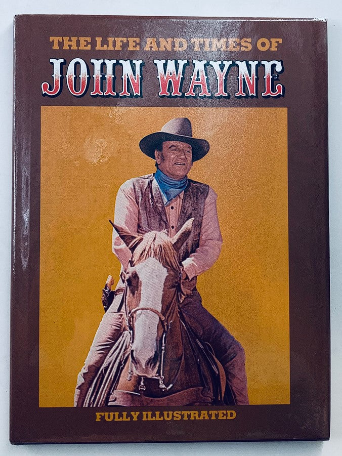 Cover image of 'The Life and Times of John Wayne,' featuring a prominent image of John Wayne on horseback, highlighting the fully illustrated format of the publication.