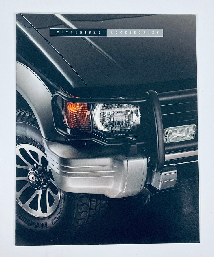 Close-up image of a 1990s Mitsubishi Accessories Dealer Showroom Sales Brochure showcasing automotive accessories, featuring the front of a Mitsubishi vehicle highlighting design details.