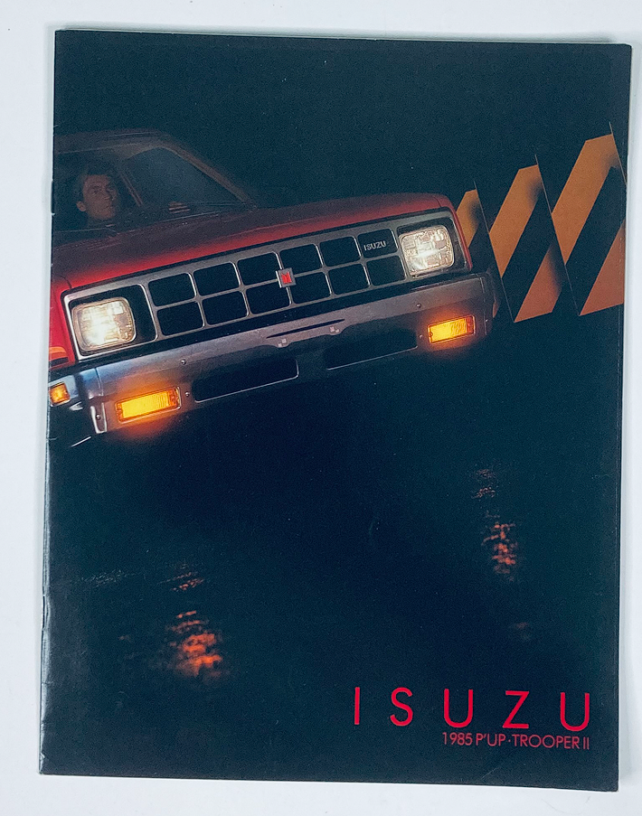 1985 Isuzu Pickup & Trooper II Dealer Showroom Sales Brochure, showcasing the vehicle design with dramatic lighting, highlighting the front grille and headlights.