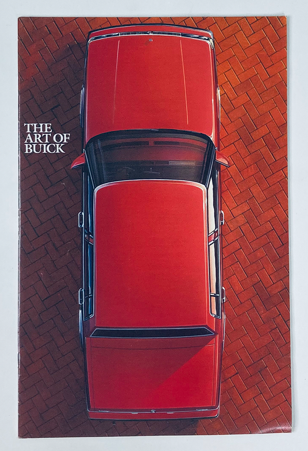1985 The Art of Buick Dealer Showroom Sales Brochure showcasing an aerial view of a red Buick car parked on a brick driveway.