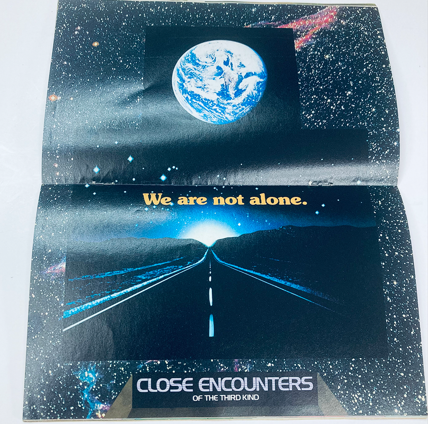Interior view of SuperMag Magazine Vol 2 No. 7 featuring a page with a cosmic theme, displaying the message 'We are not alone' alongside imagery related to 'Close Encounters of the Third Kind'.