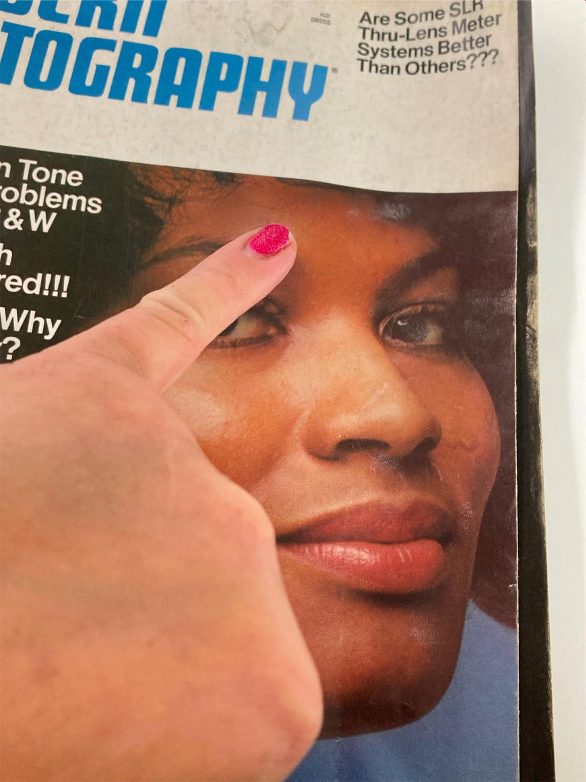 Close-up of the VTG Modern Photography Magazine July 1972 cover, highlighting the model's facial features with a finger pointing to the skin tone exposure topic.