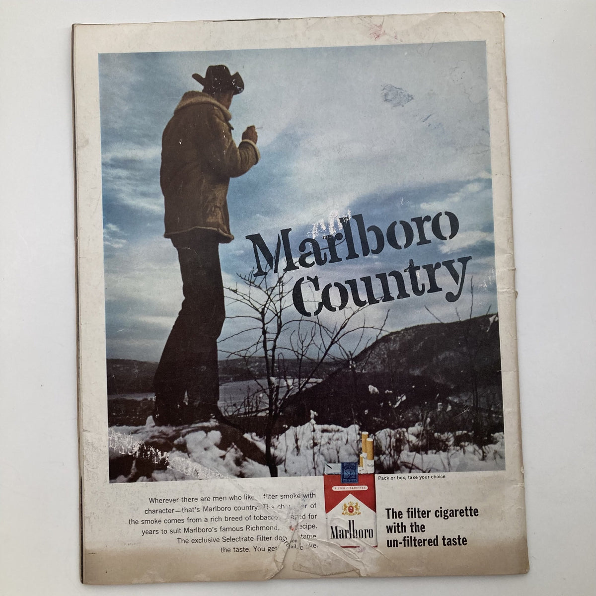 Advertisement from The Saturday Evening Post Magazine February 2, 1963, showcasing a Marlboro Country campaign with a rugged man standing in a winter landscape promoting the brand.