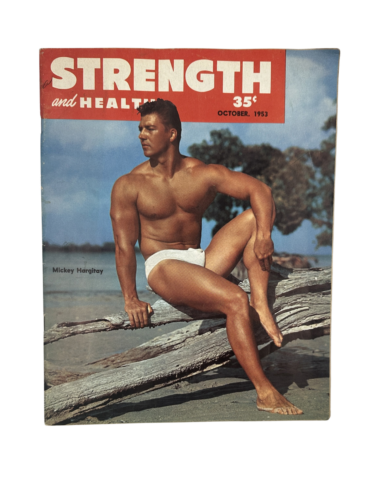 Strength and Health Magazine October 1953 featuring Mickey Hargitay on the cover, showcasing a muscular bodybuilder in a swim suit sitting on a log by the water.