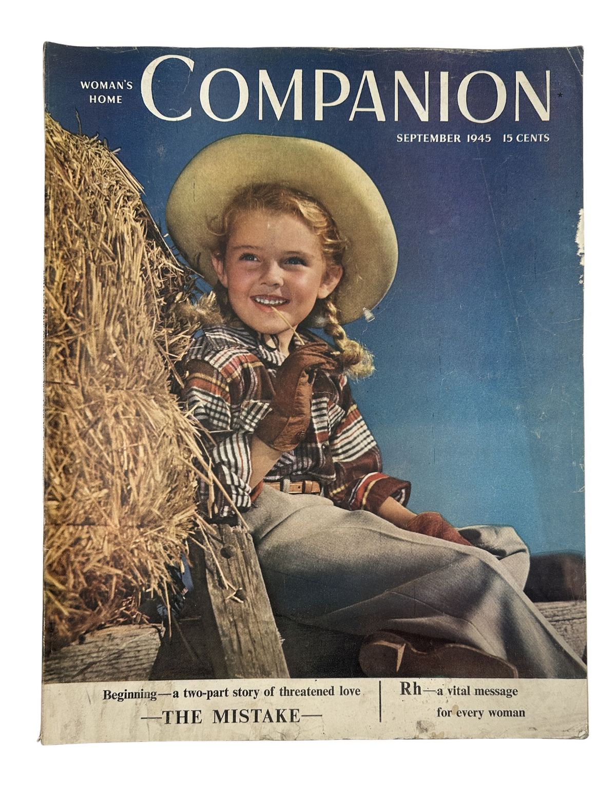 Cover of Woman’s Home Companion Magazine from September 1945 featuring the title 'The Mistake' with a smiling young girl wearing a straw hat, seated on hay bales, highlighting a two-part story of threatened love.