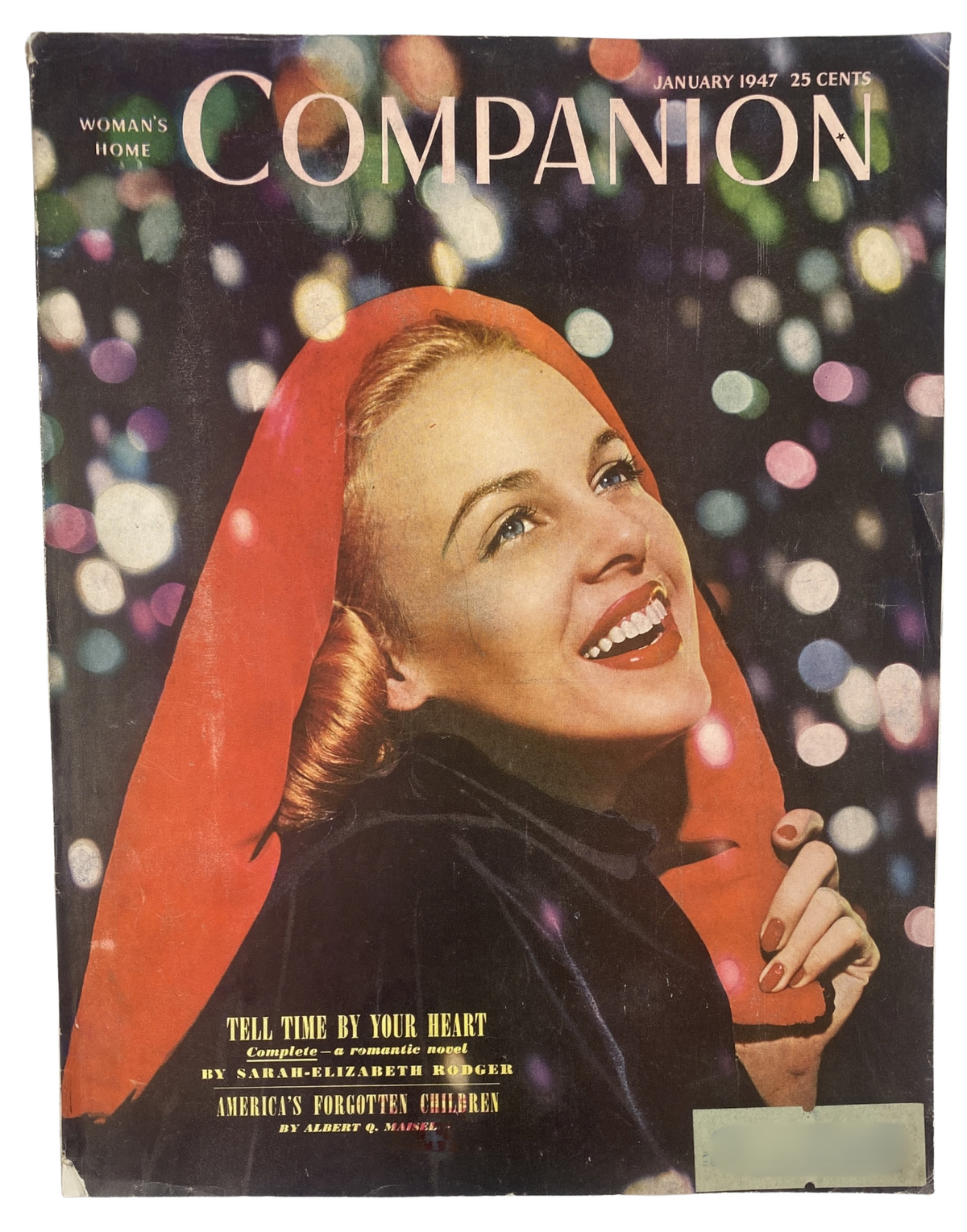 Cover of Woman’s Home Companion Magazine January 1947 featuring the title 'Tell Time by Your Heart'. The cover displays a smiling woman with blonde hair, wearing a vibrant red cape, surrounded by colorful bokeh lights.