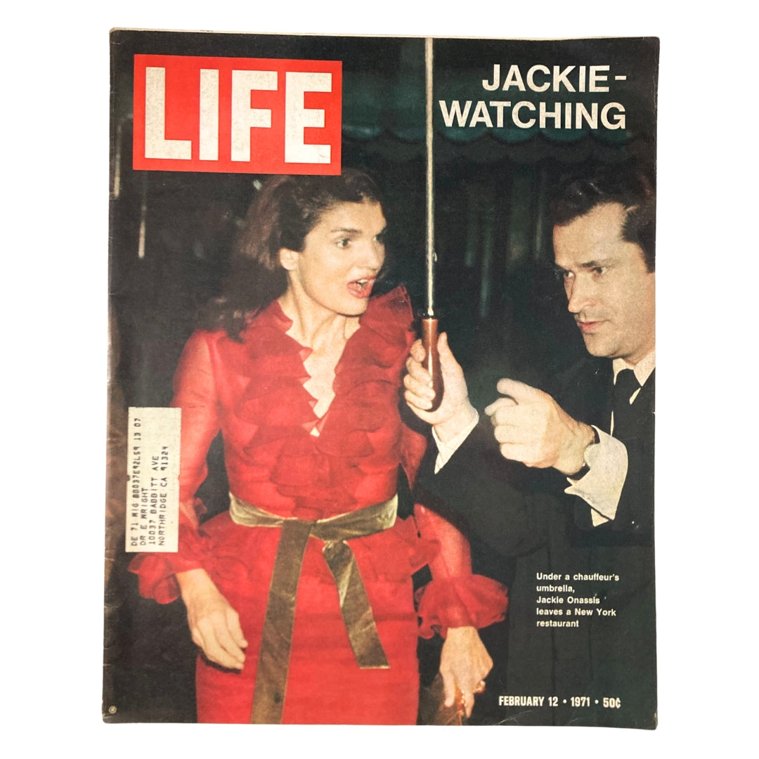 VTG Life Magazine February 12 1971 featuring Jackie Kennedy Onassis, showcasing her exiting a New York restaurant under an umbrella, dressed in a vibrant red ruffled gown.