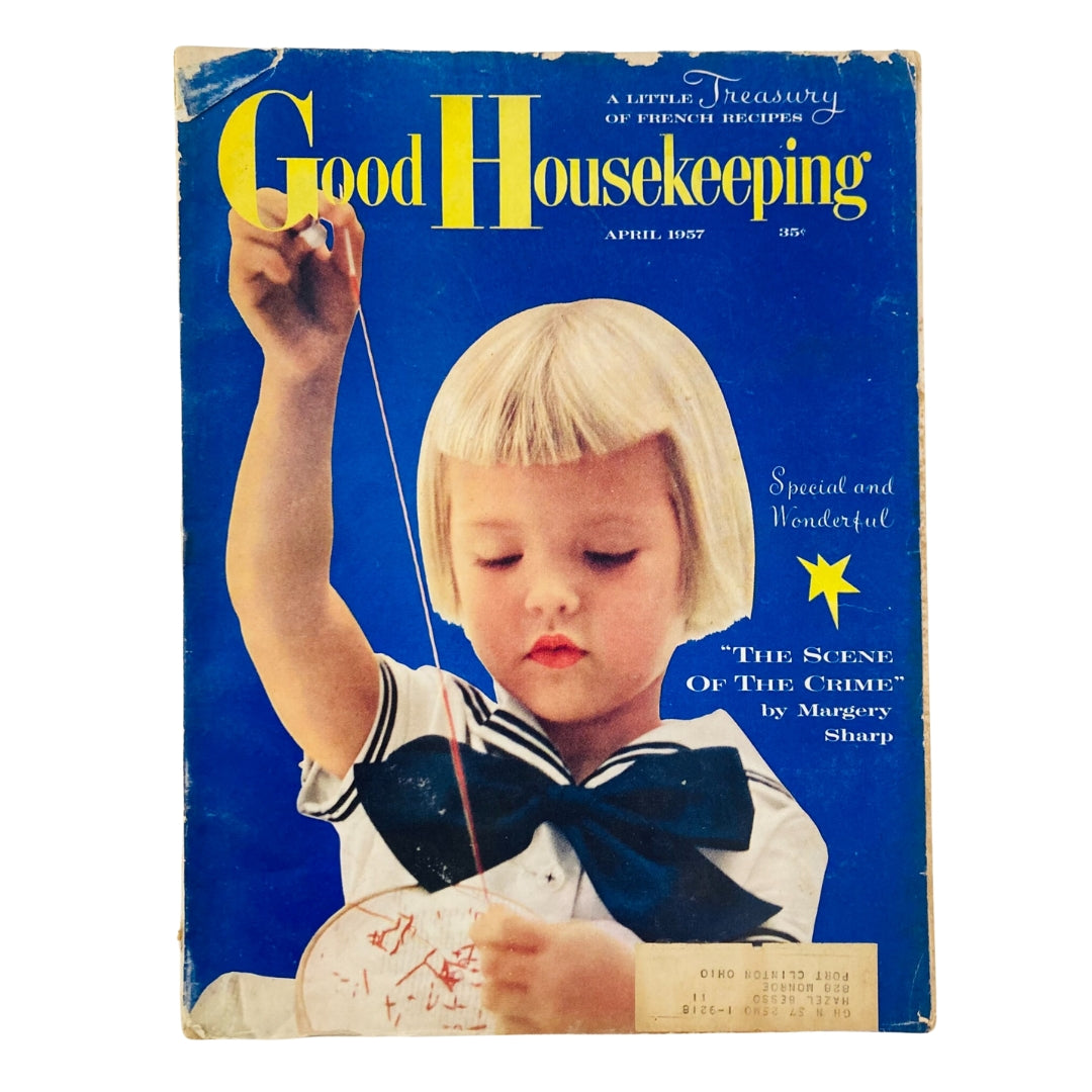 Cover of Good Housekeeping Magazine April 1957 featuring a young girl with a bob hairstyle, sewing, on a bright blue background, showcasing the theme 'Scene of the Crime'.