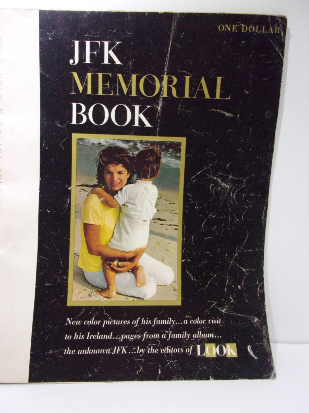 Cover of the 1964 Look Magazine: JFK Memorial Book featuring a woman holding a child on the beach, showcasing its iconic black and gold design.
