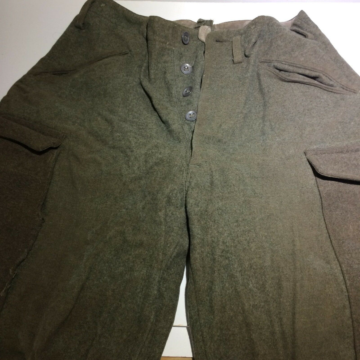 Vintage Swedish army military hunting cargo pants close-up view showing buttons and fabric texture.