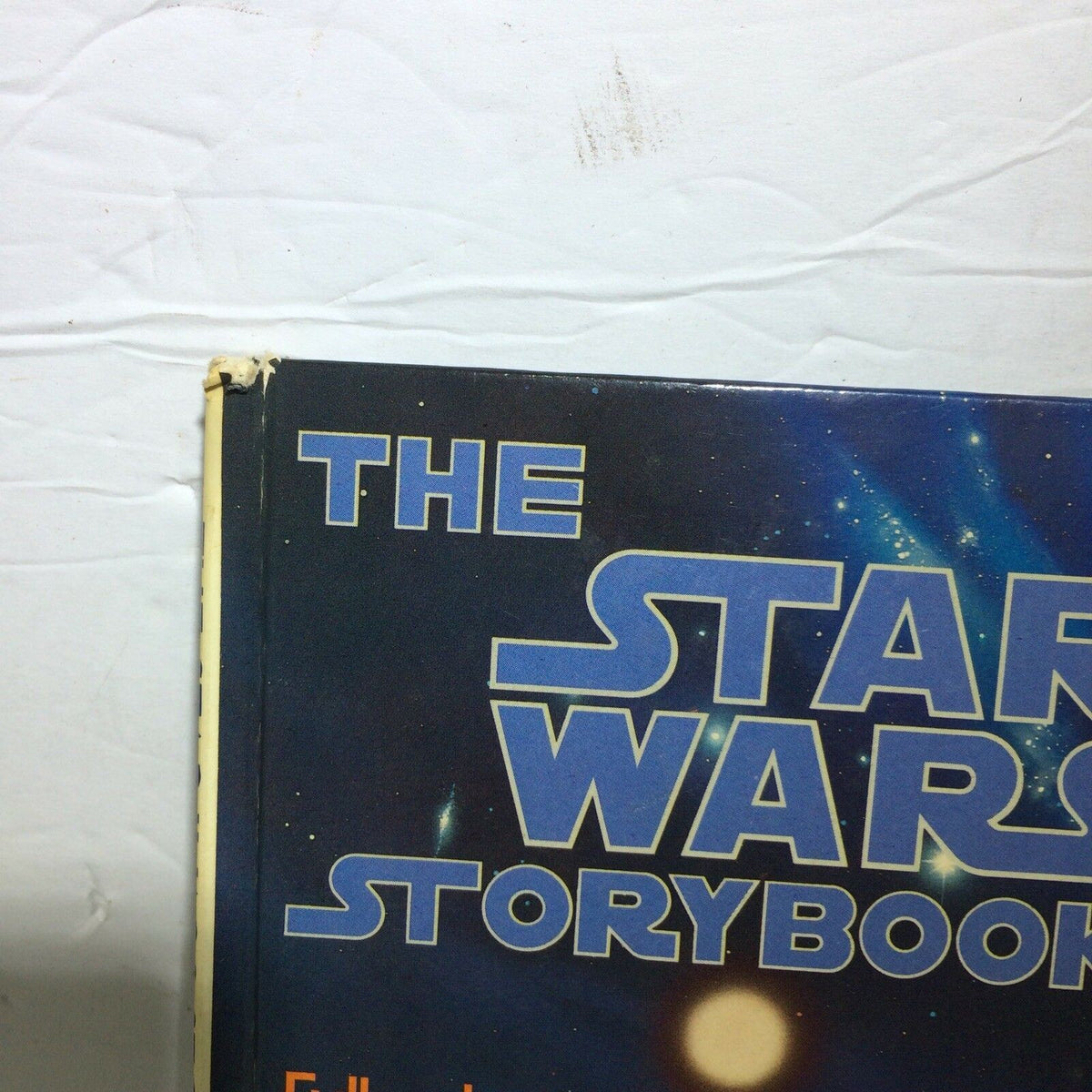 Close-up of the top of THE STAR WARS STORYBOOK hard cover, highlighting the title and space-themed background, reflecting the vintage design of this 1978 publication.