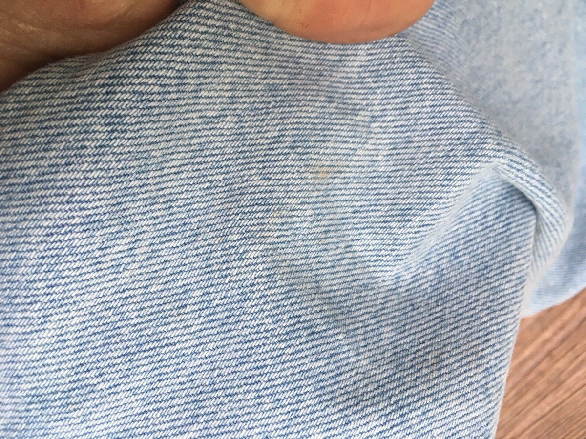 Close-up of a vintage 90s Calvin Klein high rise mom jeans in light blue denim, showcasing the fabric texture and a minor imperfection. Size 8 with straight leg fit.