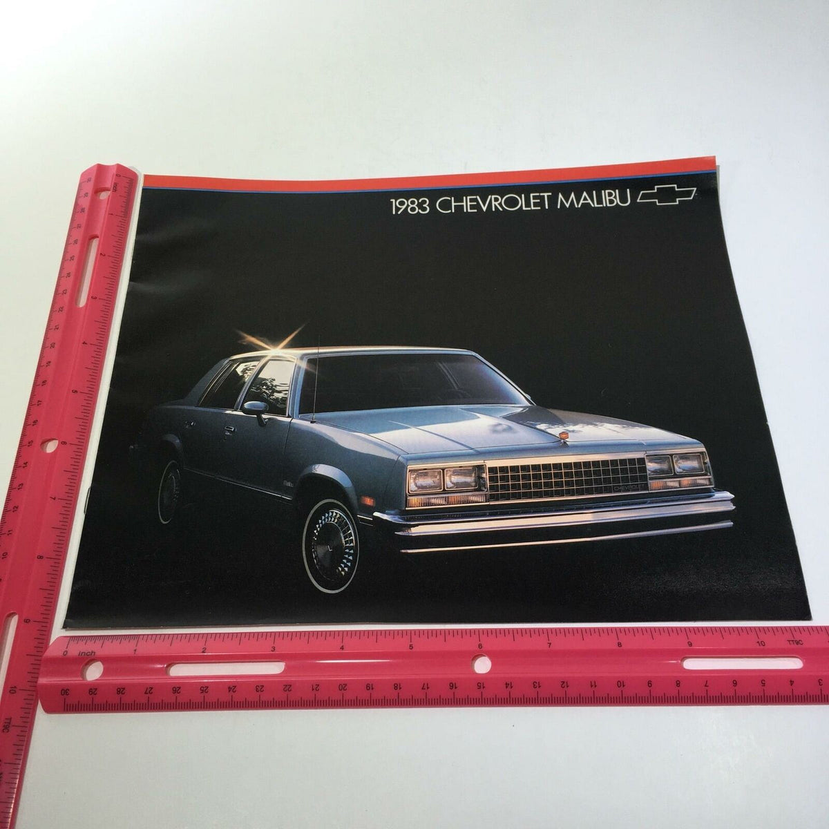 1983 Chevrolet Malibu 3.8 Liter V6 Optional V8 Engine Car Sale Brochure featuring a stylish blue sedan car on a dark background with a shiny finish.