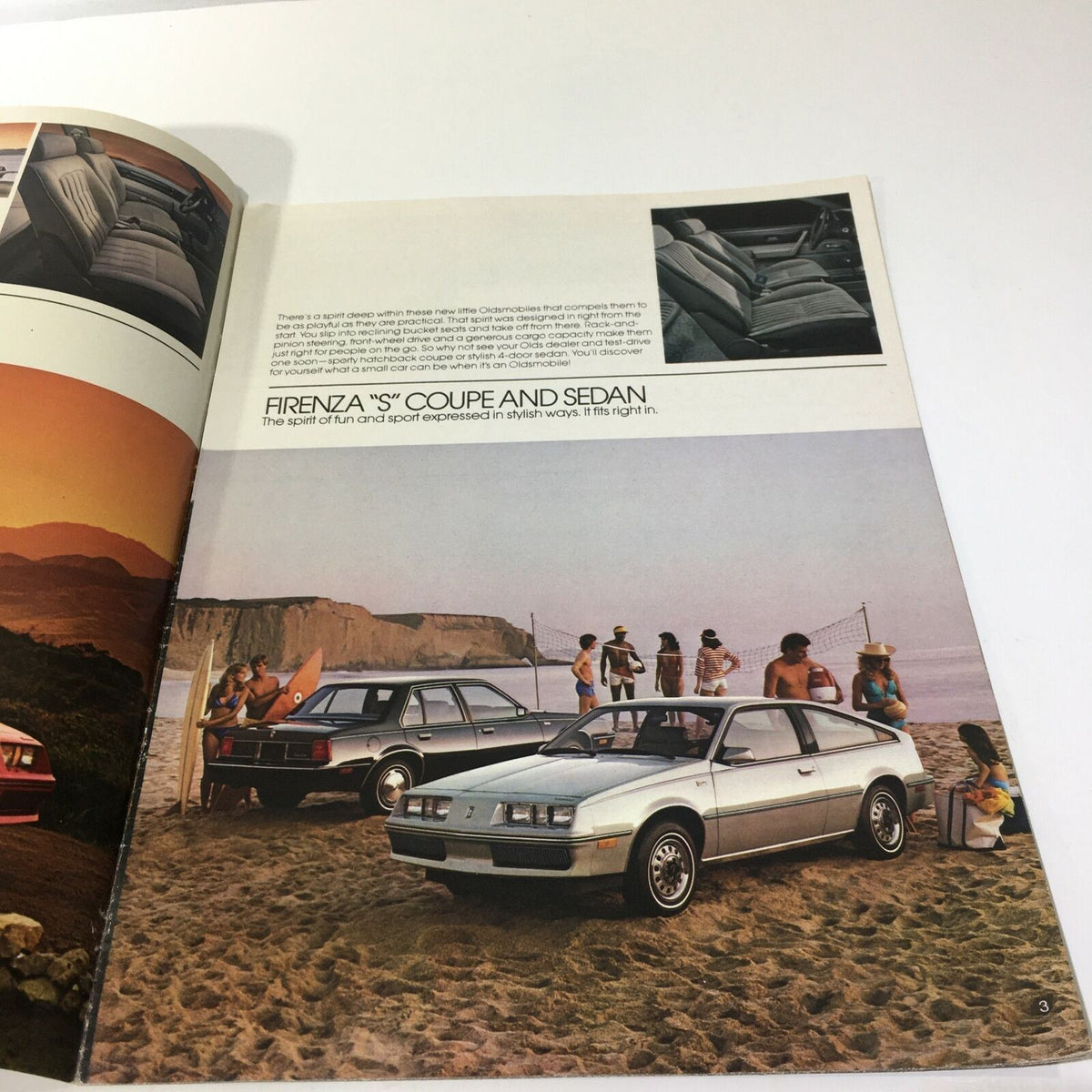 Interior page of the 1983 Oldsmobile Firenza 'S' Coupe and 4-Door Sedan brochure showcasing the Coupe model at the beach with people enjoying a sunny day.