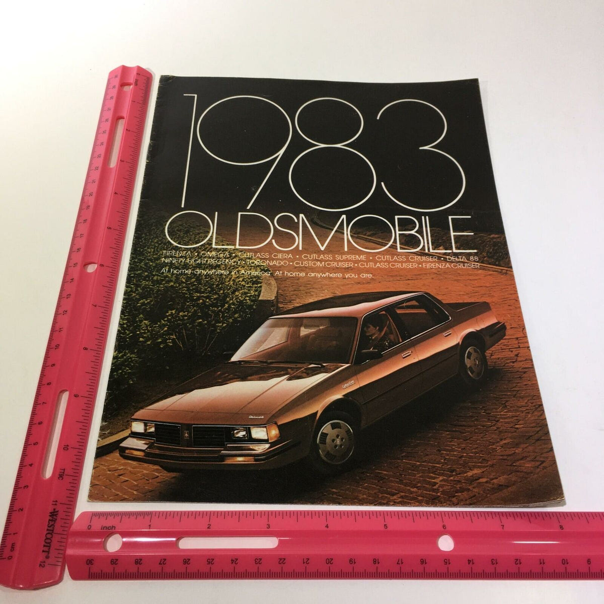 1983 Oldsmobile Firenza 'S' Coupe and 4-Door Sedan 4.3 L V-6 Engine Car Brochure, showcasing the brochure cover design with a black background and an image of the Oldsmobile car.