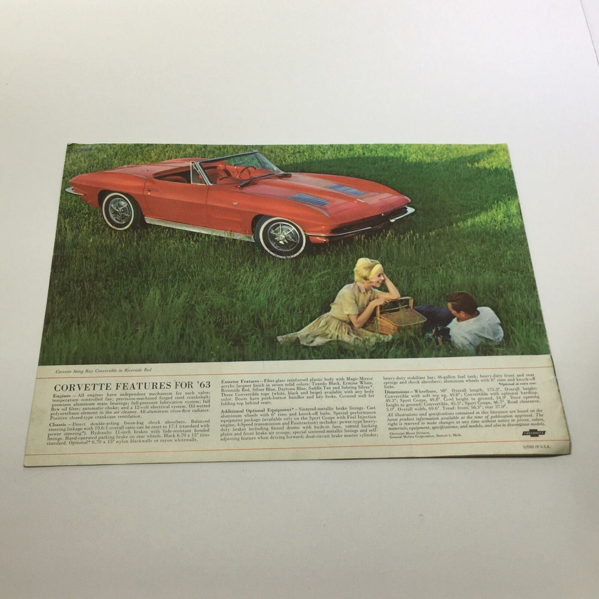 Image from the 1963 New Corvette Sting Ray Sport Coupe Sale Brochure featuring a red Corvette Sting Ray Convertible in a scenic field with two people enjoying a picnic.