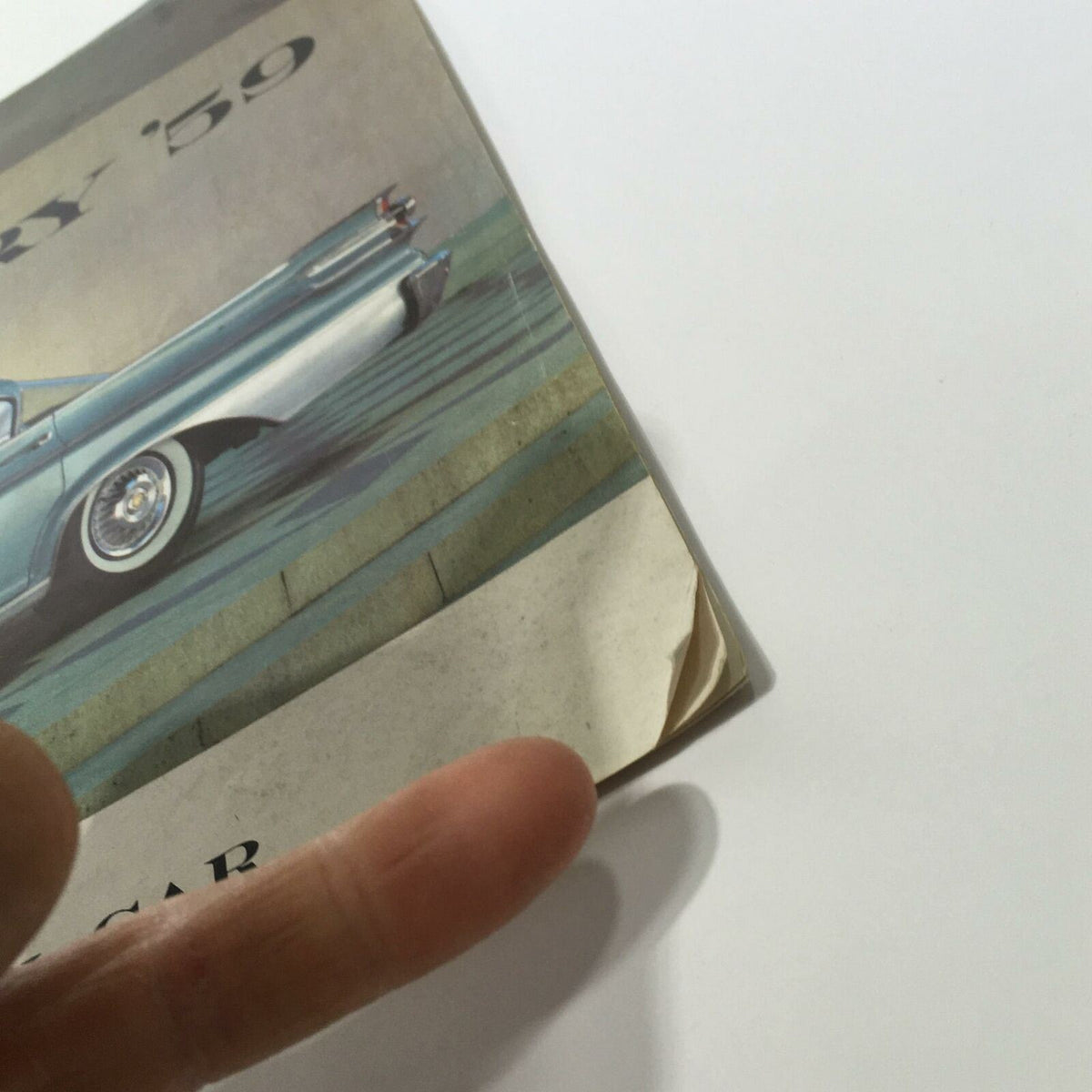 A close-up of the corner of the 1959 Mercury America's Liveliest Luxury Car Monterey 2-Door Sedan Car Brochure, showing wear and a slight tear, indicating its vintage condition.