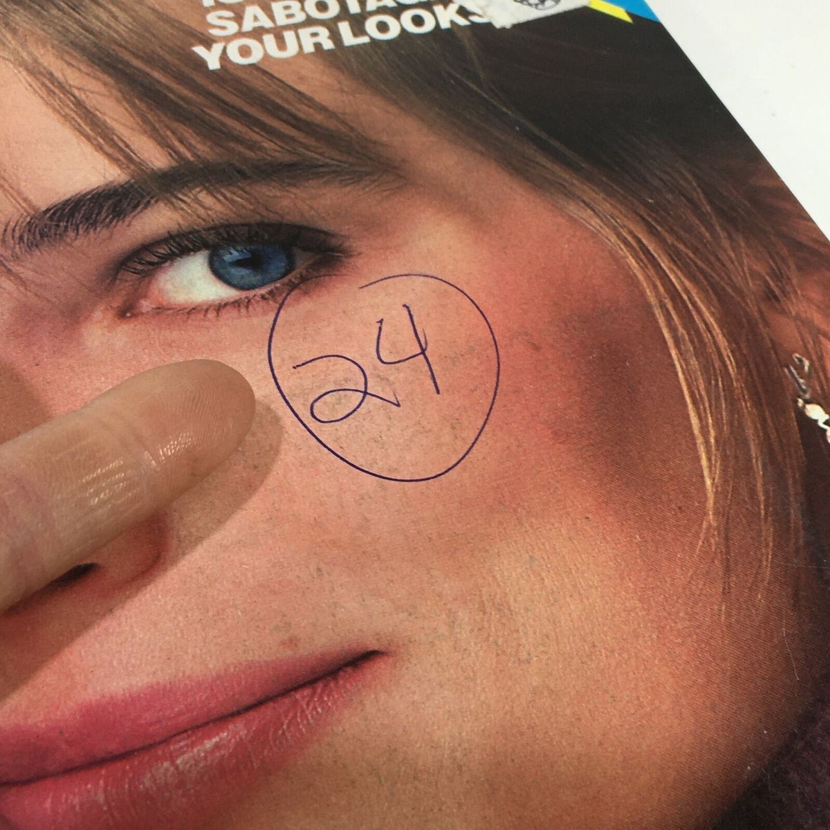 Detail shot of the VTG Glamour Magazine: March 1987 cover highlighting Paulina Porizkova's eye, with a handwritten number '24' visible.
