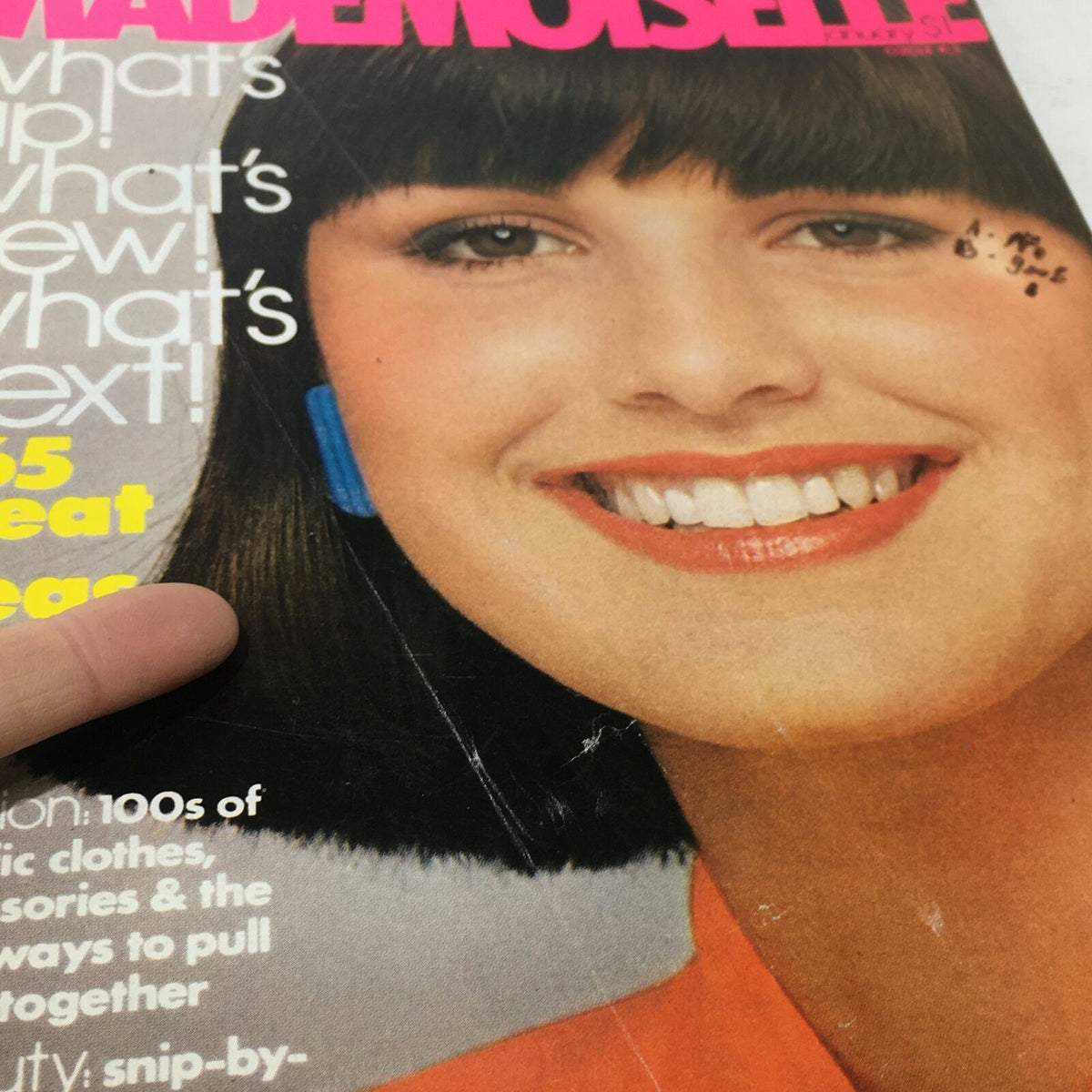 Detailed view of the VTG Mademoiselle Magazine: January 1976 cover, emphasizing the model's cheerful expression and the vibrant colors of the fashion theme.