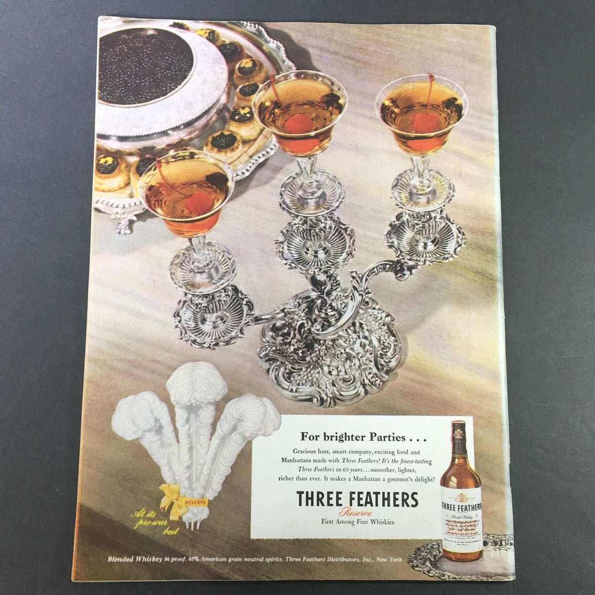 Back cover of VTG Gourmet Magazine September 1946 showcasing an advertisement for Three Feathers whiskey with elegant glasses and gourmet food presentation, emphasizing fine dining culture.