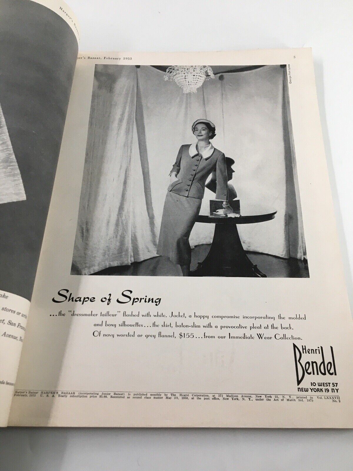 Interior page of Harper's Bazaar Magazine February 1953 showcasing a fashion model in a sophisticated outfit, complemented by a chandelier backdrop.
