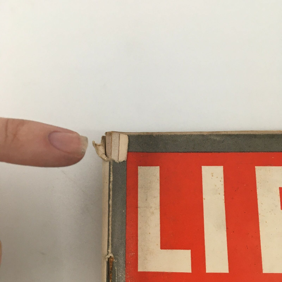 Close-up of the top corner of the VTG Life Magazine November 11, 1940, highlighting wear with a finger pointing at imperfections.