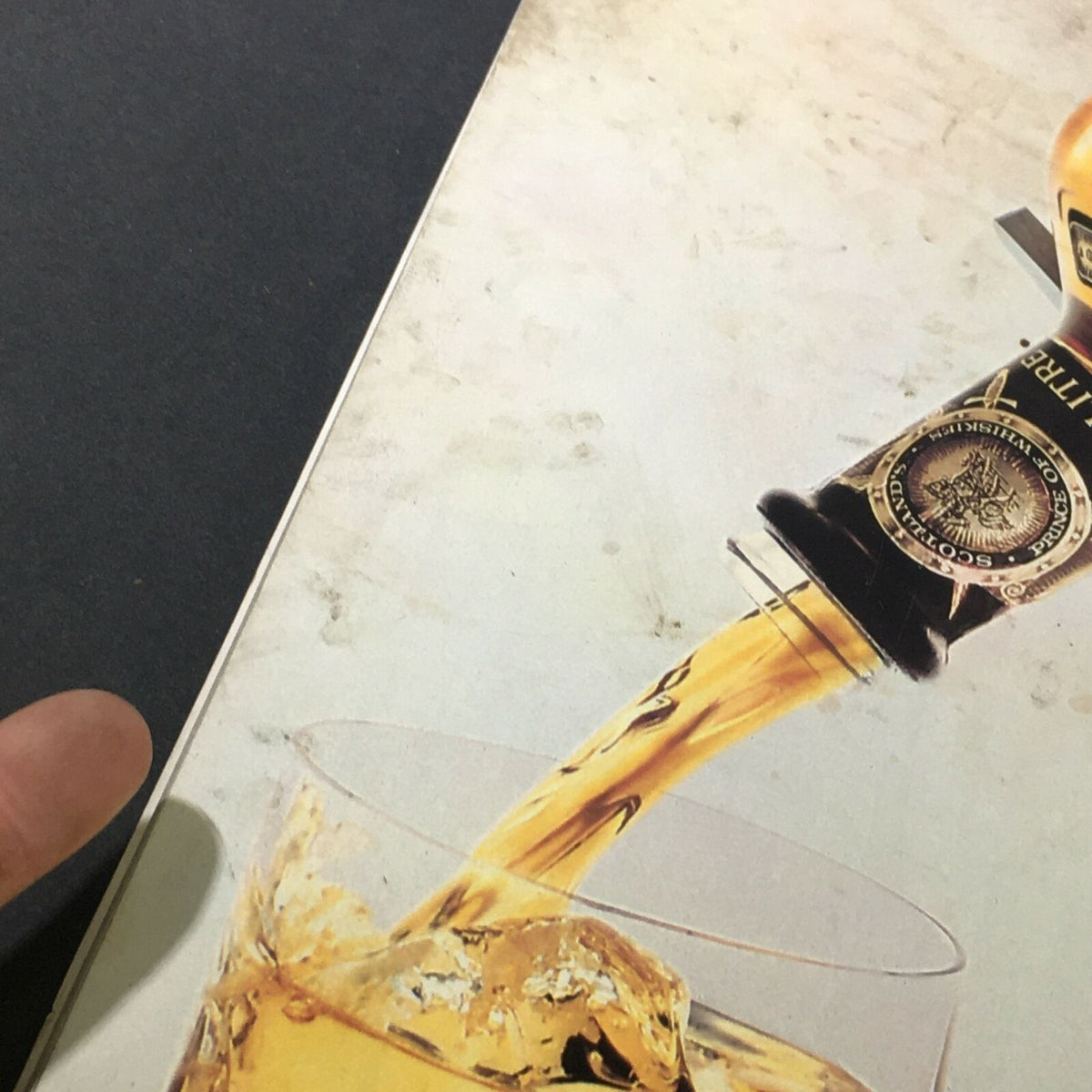 Close-up image of the pouring action of Johnnie Walker Scotch Whisky from the bottle into a glass, accompanying the VTG Life Magazine June 1986.