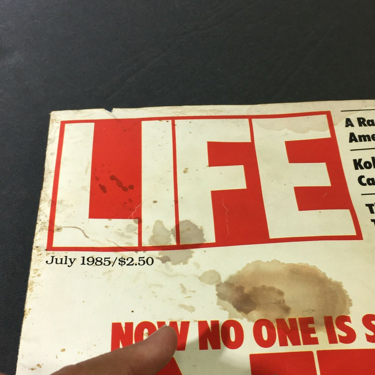 Close-up of the cover of VTG Life Magazine July 1985, highlighting the title 'LIFE', issue date, and notable stains, reflecting its vintage condition.