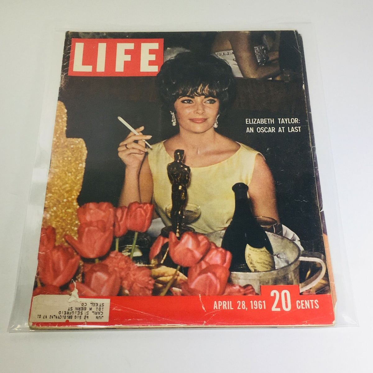 Vintage Life Magazine cover from April 28, 1961, featuring Elizabeth Taylor celebrating her Oscar win, surrounded by flowers and beverages, capturing Hollywood glamour of the era.