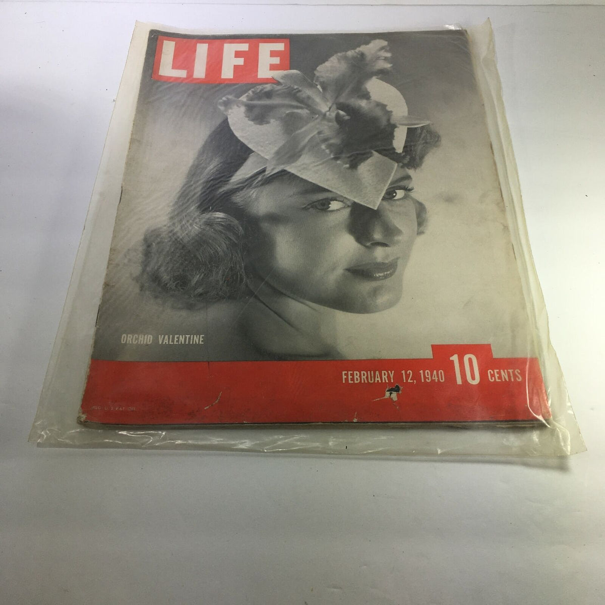 Life Magazine: February 12, 1940 - Orchid Valentine. The magazine cover features a vintage black and white photograph of a woman wearing a striking floral hat, showcasing the iconic design of the era. The cover prominently displays the date and price, reflecting its historical significance as a collectible piece.