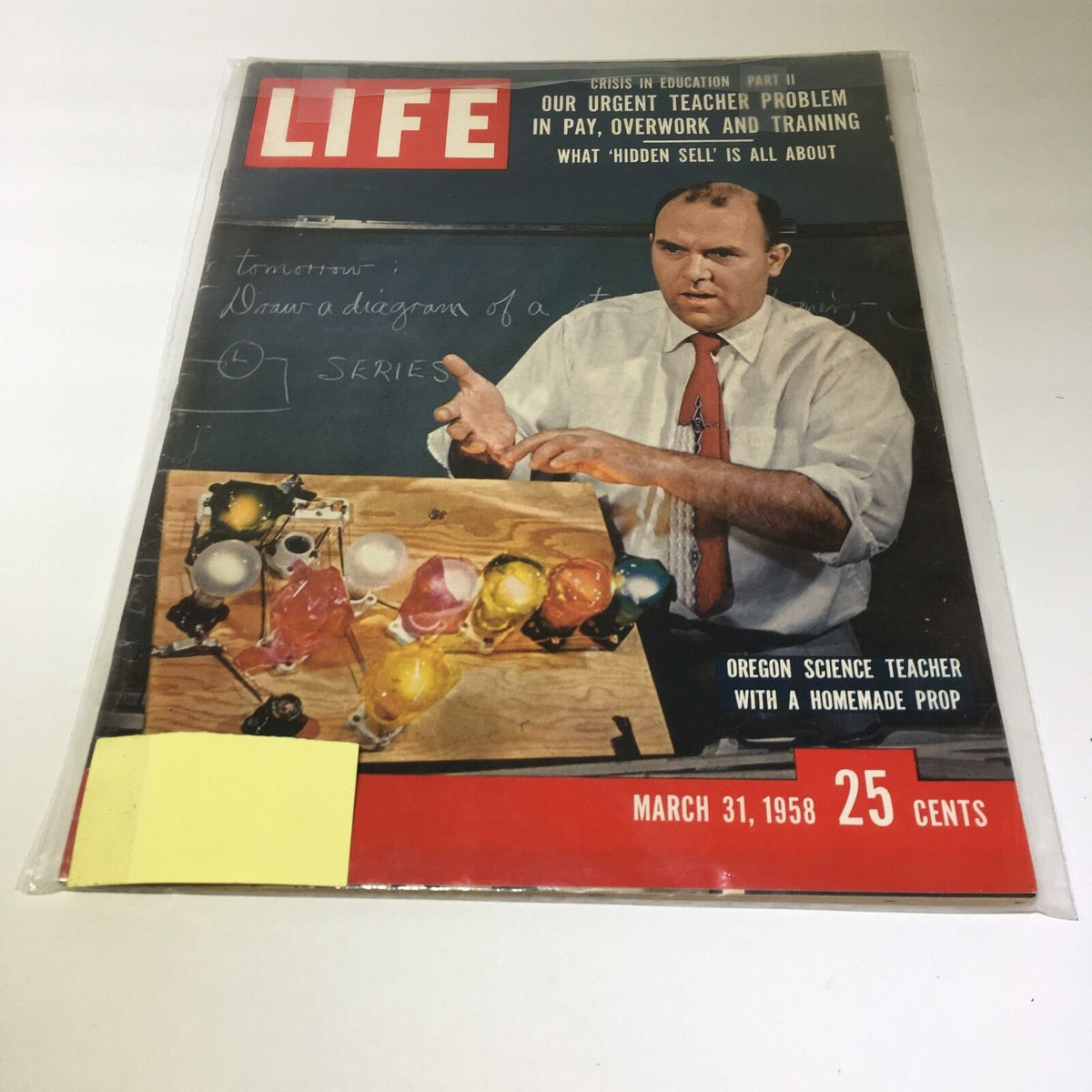 VTG Life Magazine March 31 1958 cover featuring an Oregon science teacher with a homemade prop, discussing urgent teacher issues in education, including crisis in pay, overwork, and training. The magazine is presented in protective plastic wrap.