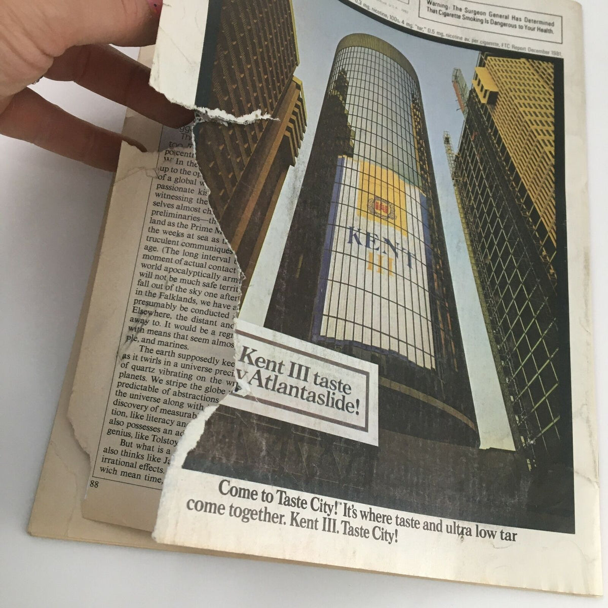 Back cover of a used Time Magazine from April 19, 1982, showing minor damage with a detailed advertisement for Kent cigarettes and the urban skyline in the background.