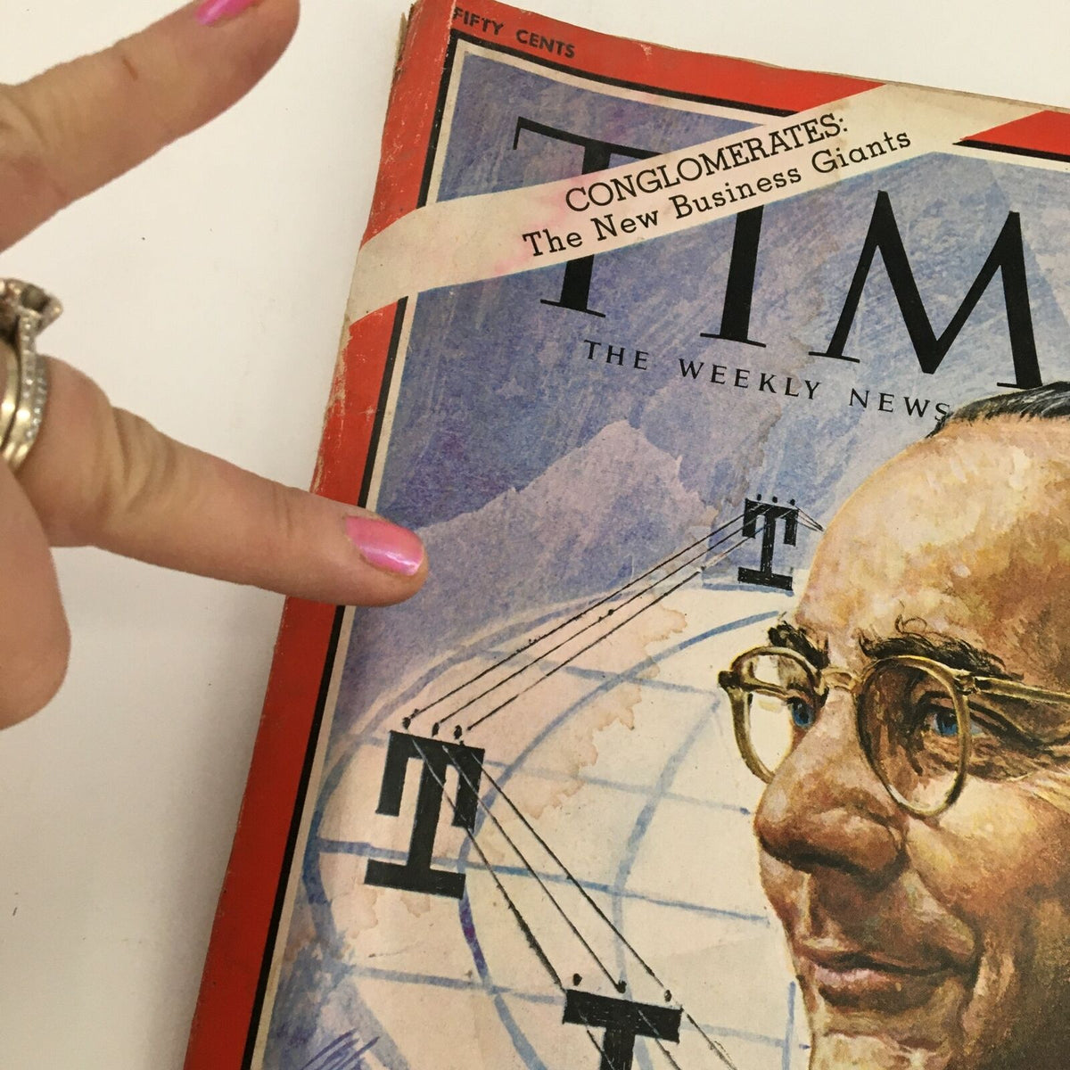 Close-up view of Time Magazine cover from September 8, 1967, highlighting ITT Corp. President Harold Geneen and the title 'Conglomerates: The New Business Giants'. The image shows a pointing finger emphasizing the details of the magazine cover.