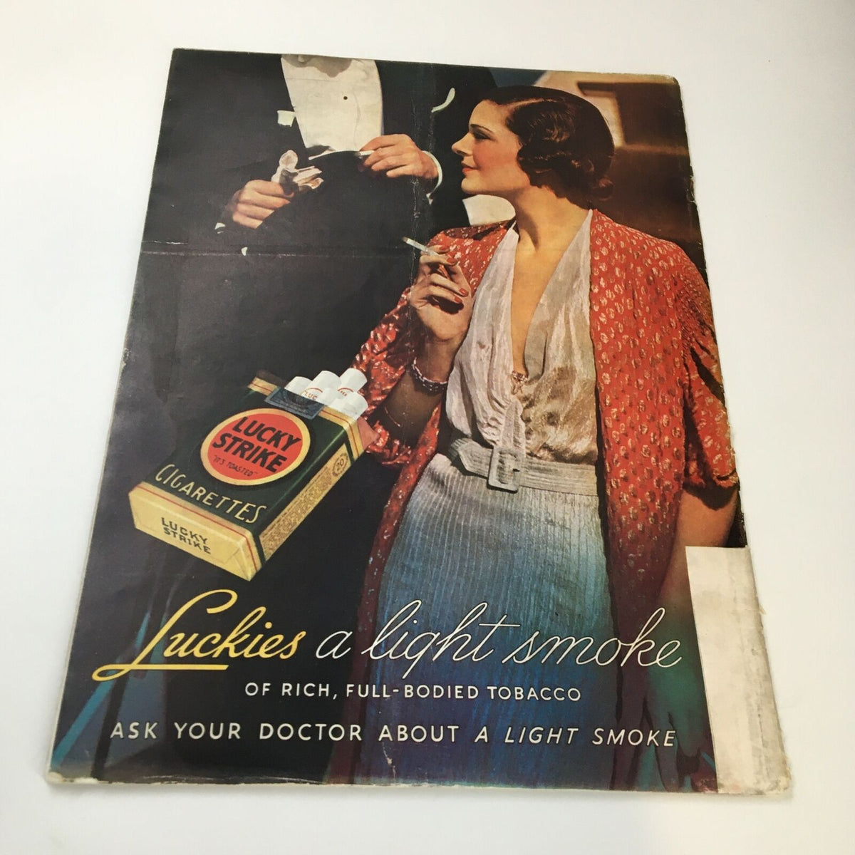 Advertisement for Lucky Strike cigarettes, depicting a stylish woman in a red robe enjoying a cigarette, reflecting 1930s fashion and social culture.