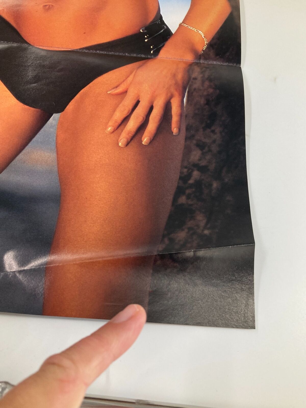 Close-up of a hand pointing to a thigh on a poster from WWE Raw Magazine October 2002 featuring Kurt Angle and Jeff Hardy.