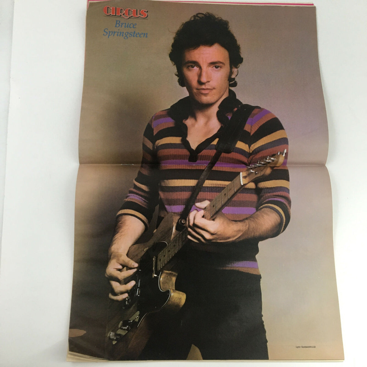Poster image of Bruce Springsteen from Circus Magazine December 31 1980, showcasing him with a guitar in a striped shirt.