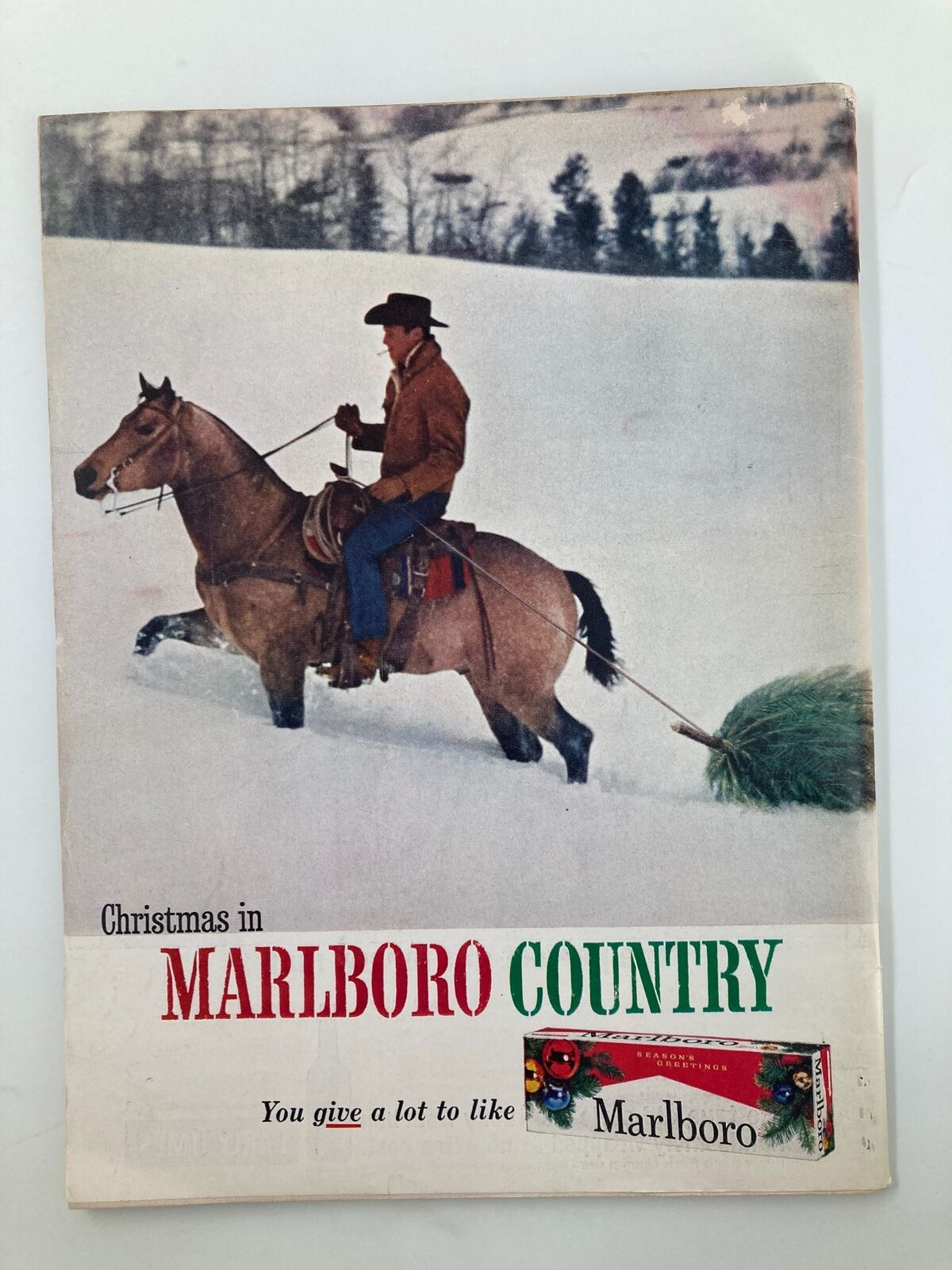 Cover of Christmas in Marlboro Country featuring a cowboy on horseback with a Christmas tree, showcasing a vintage holiday advertisement.